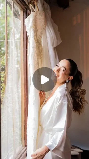 Novia en bata junto a su vestido, la mañana de la boda